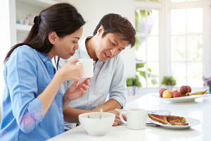 Asian Couple Reading Newspaper At Breakfast