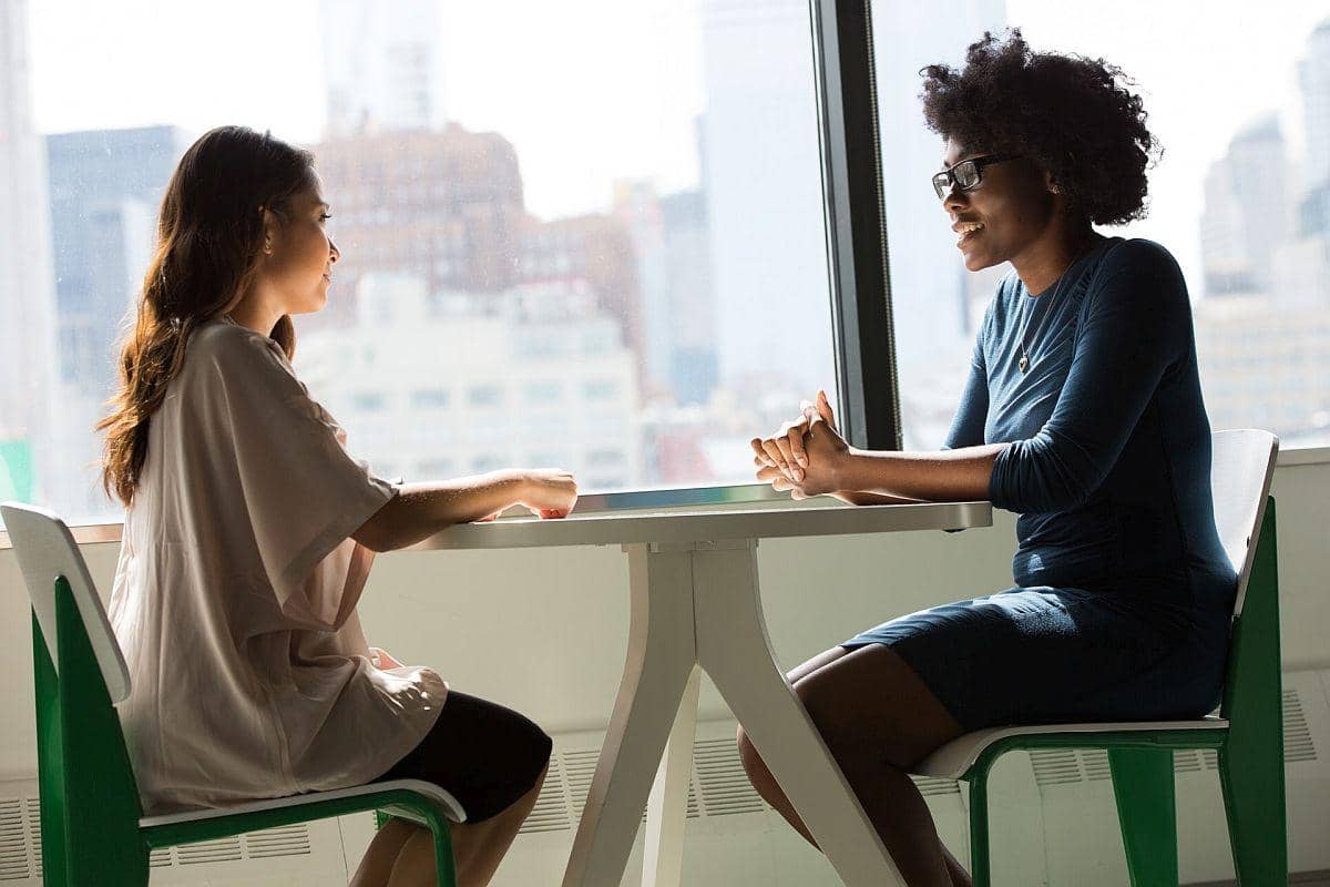 two women converse at a sunlit table; subject matter experts concept