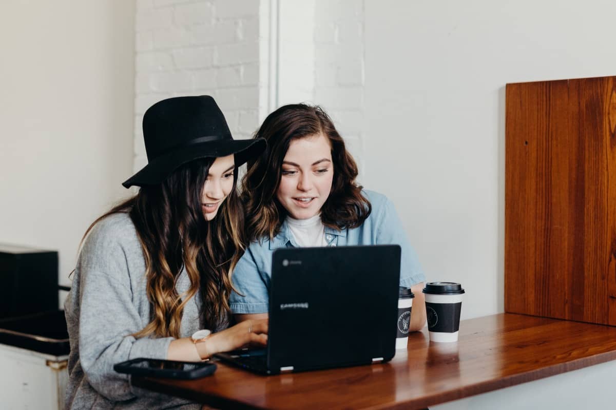 two women look at a laptop; content calendar concept