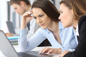 Two worried businesswomen working on line with a laptop at office